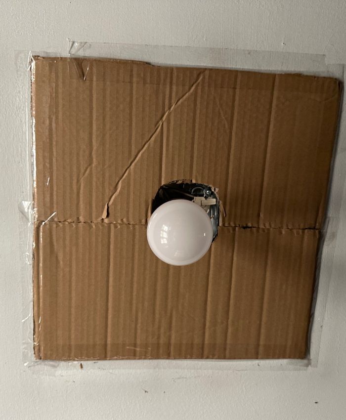 A light bulb is affixed with tape to a cardboard box