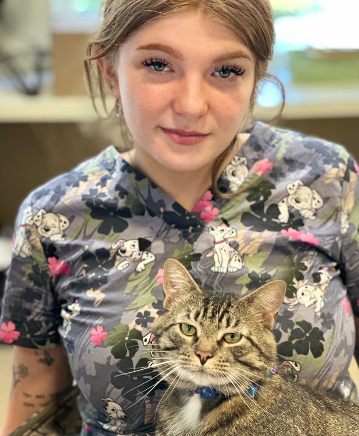 A women in a floral shirt is holding a cat